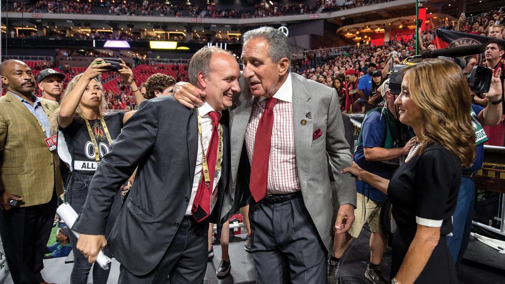 Photograph of Darren Eales ’95 hugging Falcons and Atlanta United owner Arthur Blank in a stadium